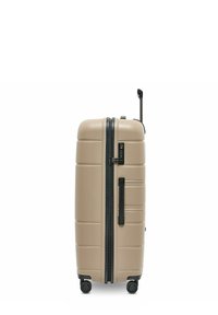 Beige harde koffer met zwarte rits, zijhandvat, combinatieslot, uitgeschoven telescopische handgreep en vier draaipolen op een witte achtergrond.