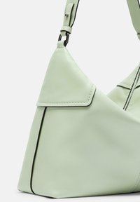 Borsa a spalla in pelle verde chiaro con forma triangolare, cuciture a contrasto e patta curvata. Presenta una tracolla nera per creare un contrasto.