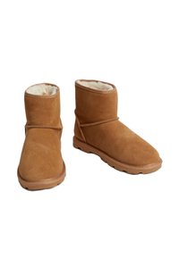 Bottines en suédine beige avec une douce doublure en fausse fourrure. Elles présentent un design simple, un bout arrondi et une semelle en caoutchouc avec des motifs de traction.