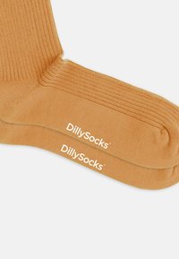 Tan ribbel sokken met een versterkte teen en hiel, voorzien van witte "DillySocks" branding aan de zijkant. Zachte, rekbare stof.