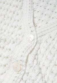 Witte gebreide cardigan met een gestructureerd patroon, v-hals, en twee grote crèmekleurige knopen aan de voorkant.