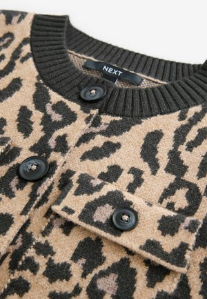 Pull beige avec imprimé léopard noir, encolure noire côtelée et boutons noirs ; possède une poche poitrine avec rabat.