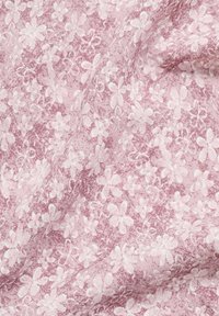 Spets tyg i rosa med ett blommönster. Texturen är mjuk och har vita blommor som är skisserade mot en subtil, mönstrad bakgrund.