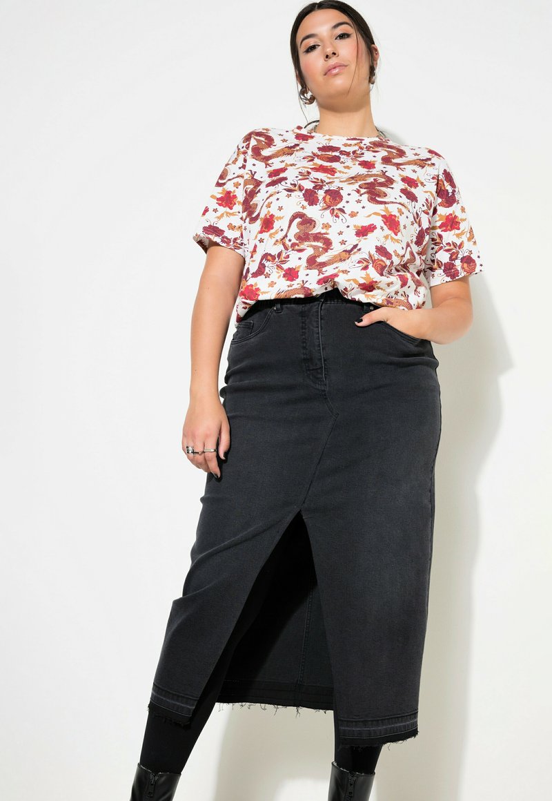 Witte kortemouwen shirt met kleurrijke bloemen- en drakenafdruk; gecombineerd met een middellange zwarte denimrok met een split aan de voorkant en een franjeonderkant.