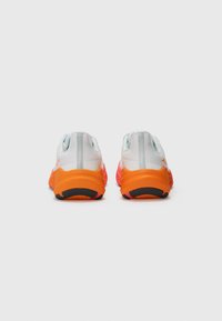 Running shoes in white, pink, and orange. Features a textured upper, padded collar, and black rubber outsole for traction.