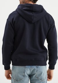 Felpa con cappuccio blu navy con una texture morbida, polsini e orlo a coste, e una vestibilità comoda. Presenta un design semplice e pulito.