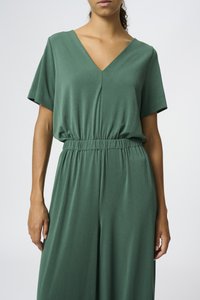 Mono verde en tela suave con escote en V, mangas cortas y cinturilla elástica. Tiene un corte relajado y diseño de pierna recta.