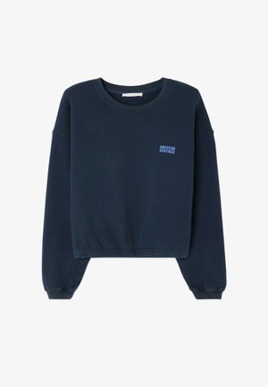 Námornícky modrý skrátený sveter vyrobený z textúrovanej látky. Má dlhé rukávy a malú modrú nálepku "American Vintage" na ľavej hrudi.