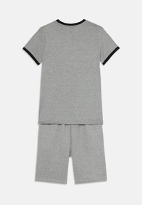Grijze katoenen set bestaande uit een t-shirt met korte mouwen met zwarte bies en bijpassende shorts. Zachte textuur en een relaxte pasvorm.