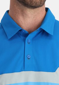 Blauwe poloshirt met een patroonontwerp; voorzien van een klassieke kraag en twee blauwe knopen. Het materiaal lijkt zacht en heeft een lichte glans.