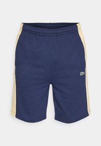 Shorts de sport bleu marine avec accents jaunes sur les côtés, taille élastique et logo brodé vert. Confection en tissu doux et flexible.