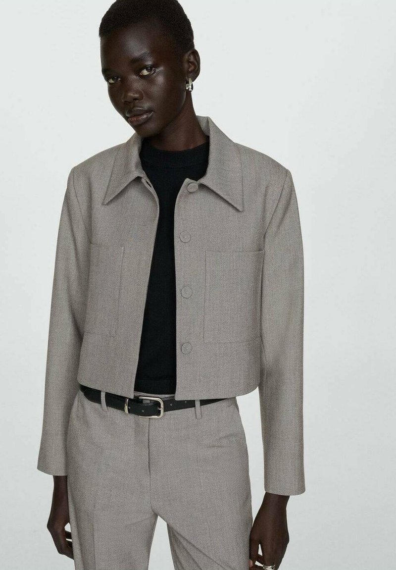 Blazer grigio accorciato realizzato in tessuto testurizzato, con colletto a punta, chiusura con bottoni anteriori e due ampie tasche applicate.