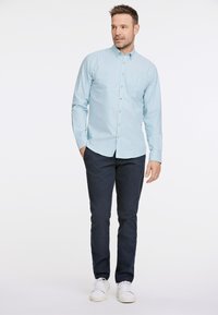 Camicetta button-up a righe blu chiaro e bianche, in cotone, abbinata a pantaloni chinos blu navy e sneakers bianche, con colletto classico e maniche lunghe.