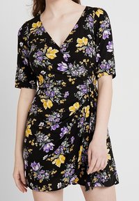 Schwarzes florales Wickelkleid mit kurzen Ärmeln. Verfügt über gelbe und lila Blumen, einen tiefen V-Ausschnitt und geraffte Details an der Taille.