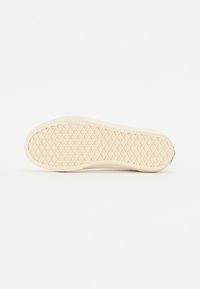 Semelle de basket couleur blanc cassé avec motif en diamant et gaufré, talon plat et arche légèrement surélevée sur fond blanc.