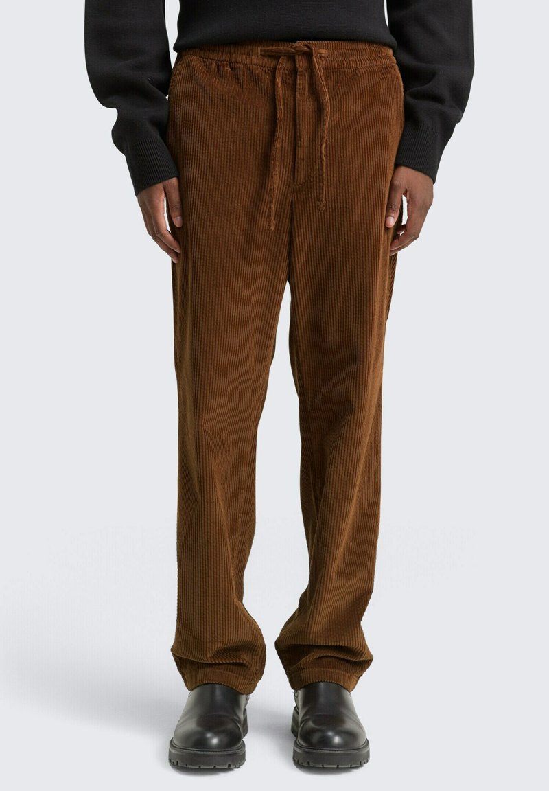 Bruine corduroy broek met een relaxte pasvorm, voorzien van een elastische tailleband, trekkoordsluiting en verticale ribbeltextuur.