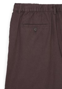 Pantalons en tissu marron avec une finition texturée, dotés d'une taille élastique et d'une poche arrière avec fermeture à bouton.