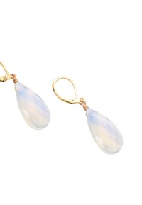 Guldtonade hängande örhängen med päronformade, fasetterade opalescerande stenar med en slät yta. Krokar för säker användning.