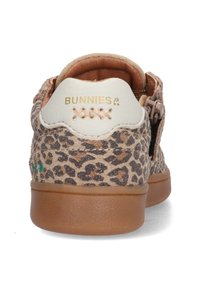 Baskets en imprimé léopard avec une surface texturée, dans des couleurs beige et marron, un talon blanc avec un logo doré et une fermeture éclair sur le côté.