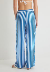Lange, loszittende broek met verticale blauwe en witte strepen. Gemaakt van lichtgewicht stof met een elastische tailleband en zijzakken.