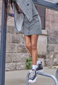 Jacka och kjol med hundtandmönster i svart och vitt, kombinerad med högskoroliga sneakers. Har knappar och detaljer med texturerad tyg.