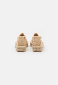 Beige espadriller med et teksturert stoffoverdel og frynsete kanter, med en vevd jutesåle for bedre grep og komfort.