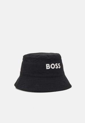 Chapeau seau noir en tissu, doté d'un bord cousu et d'un grand logo blanc "BOSS" sur un côté. Texture lisse, design simple.