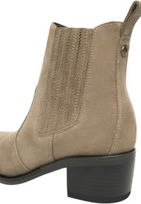 Beige suède enkellaarsje met elastische zijpanelen, gestikte details en een lage blokhak; gladde textuur en gestroomlijnd ontwerp.