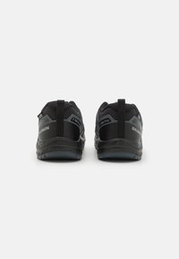 Chaussures de sport noires avec upper en mesh et en synthétique. Elles disposent d'un tirant à l'arrière, d'un renfort à l'avant et d'accents gris. Semelle en caoutchouc pour l'adhérence.