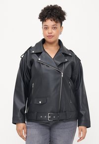 Black faux leather biker jacket with silver zippers, a belted waist, wide lapels, and shoulder epaulets. Textured surface and relaxed fit.