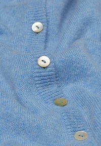 Lichtblauwe gebreide cardigan met een geribbelde textuur, voorzien van vijf ronde, lichtgekleurde knopen van schelp. Zachte, gezellige uitstraling.