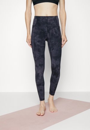 Czarnie legginsy z wysokim stanem w wzór tie-dye, wykonane z elastycznego materiału. Posiadają detale szwów oraz dopasowany krój.