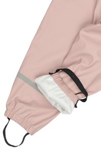 Chaqueta impermeable de color rosa claro con puños elásticos y forro blanco. Presenta una franja gris y una banda elástica negra para un ajuste ajustable.