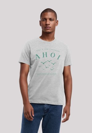 Gray cotton t-shirt featuring the text "AHOI" in green, with a design of flying birds and brand details printed above and below.