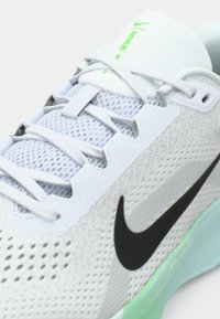 Λευκό αθλητικό παπούτσι με διχτυωτό ύφασμα, μαύρο λογότυπο swoosh, πράσινες λεπτομέρειες και υφή στην σόλα. Διαθέτει σχέδιο με κορδόνια και επενδυμένο κολάρο.