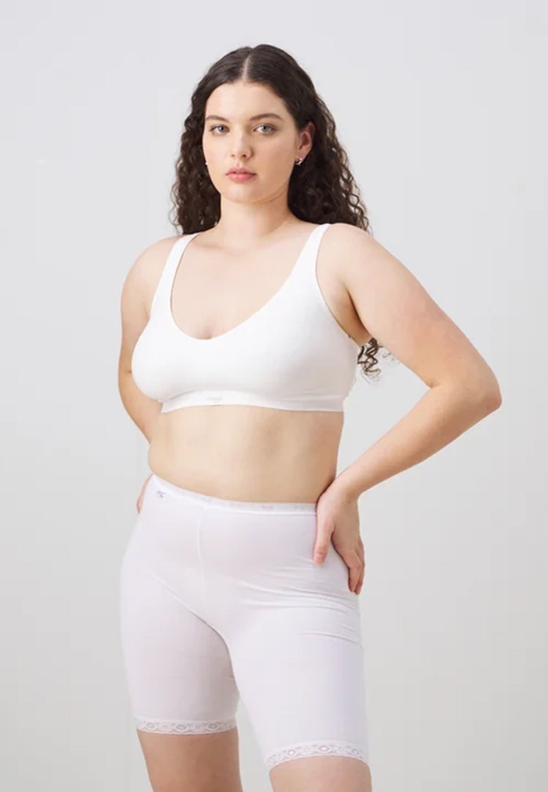 Set di bralette e pantaloni corti bianchi senza cuciture, caratterizzato da una texture morbida, spalline larghe e bordino in pizzo sui pantaloni, progettato per comfort e semplicità.