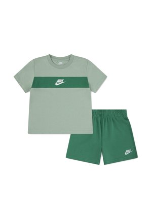 Lichtgroen Nike T-shirt met een donkergroene horizontale streep en logo, gecombineerd met bijpassende donkergroene Nike shorts met elastische tailleband.