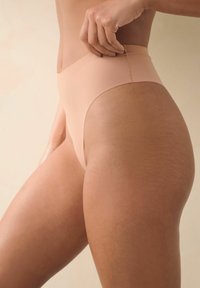 Sous-vêtements taille haute nude fabriqués en tissu lisse, avec un design sans couture, une bande élastique douce et une couverture minimale sur les côtés.