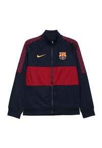 Navy ja punainen urheilujakki vetoketjulla, jossa on ruutukuviot hihoissa, Nike-logot ja Barcelona-embleemi vasemmalla rinnalla. Sileä kangas.