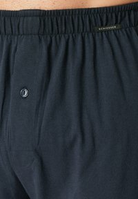 Pantaloni boxer di cotone blu scuro con una texture morbida, dotati di chiusura a bottoni e cintura elastica. Etichetta con logo Schiesser visibile.