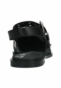 Zwarte leren sandaal met een platte zool, achterste enkelband en zilveren gespdetail. Het interieur heeft een effen zwarte inlegzool met branding.