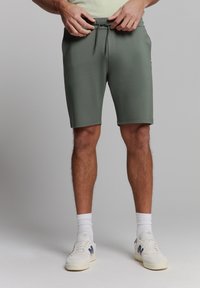 Groene, knielange shorts gemaakt van zachte stof met een elastische tailleband en trekkoord. Voorzien van zijzakken en een slim fit ontwerp.