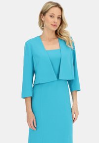 Turkusowa sukienka z kwadratowym dekoltem oraz skróconą kurtką z rękawami do trzech czwartej długości, wykonaną z gładkiego, teksturowanego materiału.
