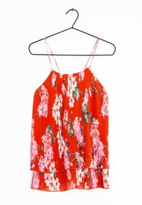 Rote Bluse mit floralem Muster und dünnen Trägern, mit plissierter Textur und geschichtetem Saum. Akzente von rosa Blumen und grünen Blättern überall.