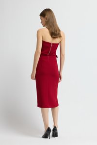 Rotes trägerloses Kleid mit tailliertem Oberteil, knieumspielendem Bleistiftrock, Reißverschluss am Rücken und einem dezenten Schleifenakzent an der Taille.