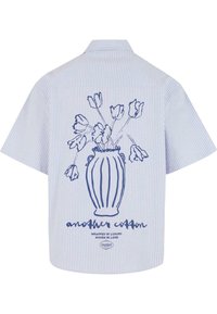 Camicia a maniche corte in cotone a righe blu e bianche, con un'illustrazione di un vaso di fiori e il testo del marchio sul retro.