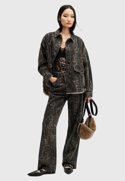Veste en denim noir et pantalon avec un motif léopard, présentant des bords effilochés. Haut en dentelle noire en dessous, portant un sac texturé marron. Chaussures plates noires.