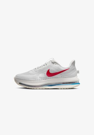 Chaussure de sport blanche avec un dessus en mesh respirant, un emblématique swoosh rouge de Nike, une semelle rembourrée avec des accents bleus et des détails texturés.