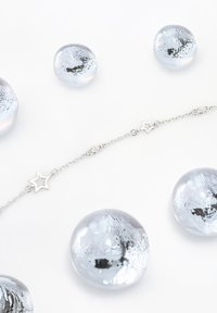 Bracciale in argento con accenti a forma di stella e perline di argento lucido, su uno sfondo bianco.