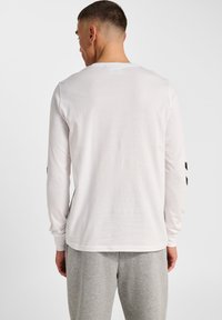 Biały T-shirt z długim rękawem wykonany z bawełny, z okrągłym dekoltem i czarnymi akcentami na rękawach. Gładka faktura i luźny krój.